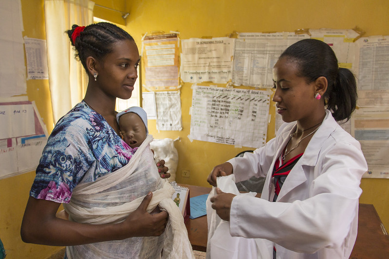 Nurse helping woman practice baby wearing