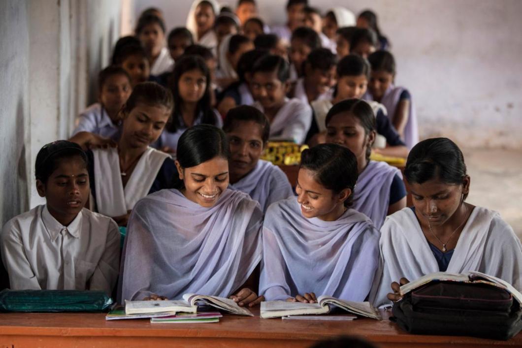 Girls in a classroom looking at textbooks.