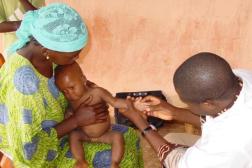 Health worker caring for small child on mother's lap