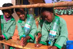 School girls washing their hands at a water station made from used water bottles.