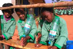 School girls washing their hands at a water station made from used water bottles.