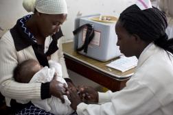 Nurse administering vaccine on newborn in mother's lap