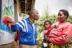 Homme pointant sur une affiche devant une femme et un enfant