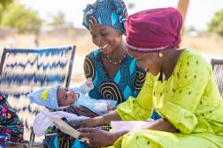 Two women smiling holding a baby