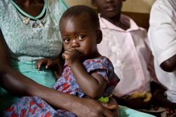 Enfant suçant le pouce assis sur les genoux de sa mère