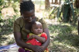 An African mother looks at her baby in her arms and holds her baby.